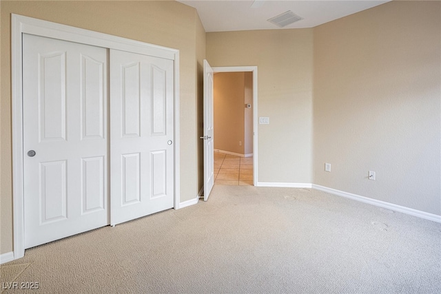 unfurnished bedroom with a closet and light colored carpet