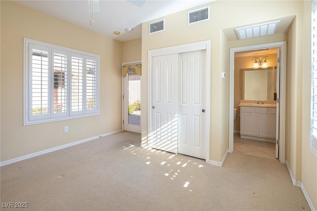 unfurnished bedroom with ceiling fan, a closet, light colored carpet, and multiple windows