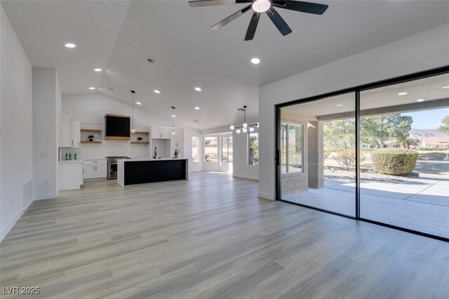 unfurnished living room featuring vaulted ceiling, ceiling fan with notable chandelier, light hardwood / wood-style flooring, and sink