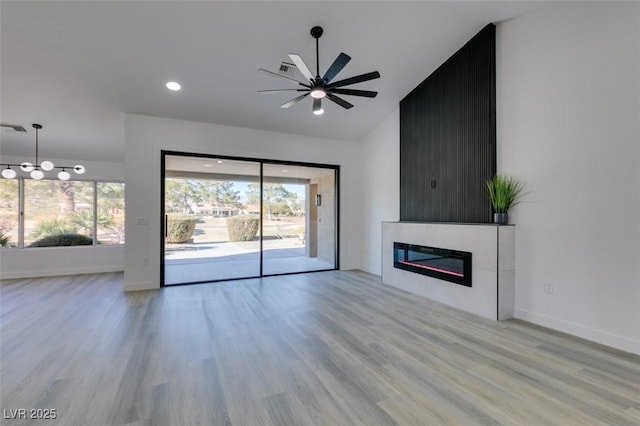 unfurnished living room featuring ceiling fan, light hardwood / wood-style floors, a tile fireplace, and lofted ceiling