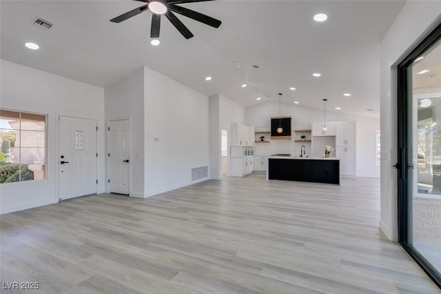 unfurnished living room featuring ceiling fan, lofted ceiling, light hardwood / wood-style floors, and sink