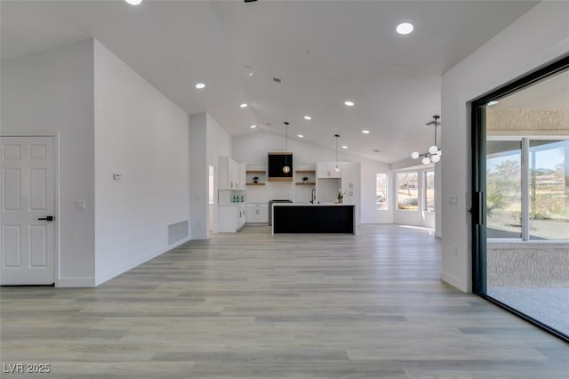 unfurnished living room with high vaulted ceiling and light wood-type flooring