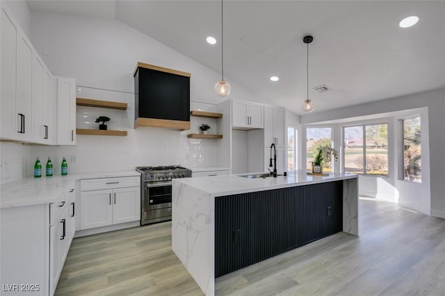 kitchen featuring decorative light fixtures, high end stove, sink, and white cabinetry