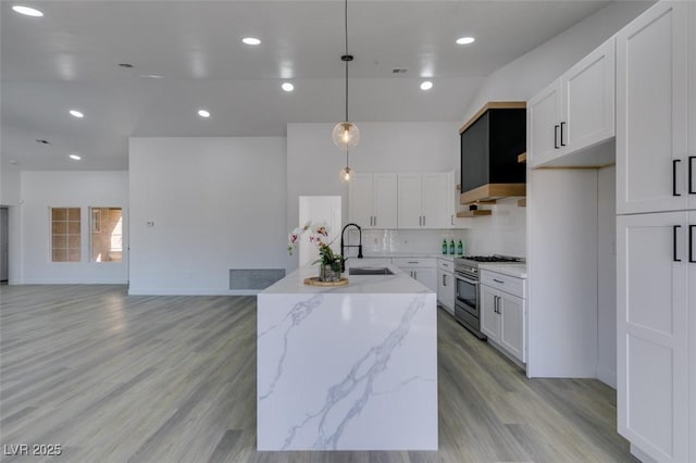 kitchen with high end stainless steel range oven, a kitchen island with sink, pendant lighting, white cabinets, and light stone counters