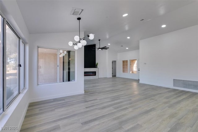 unfurnished living room featuring ceiling fan with notable chandelier, a fireplace, and a healthy amount of sunlight