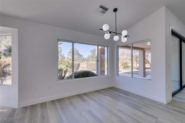 unfurnished dining area featuring light hardwood / wood-style flooring, an inviting chandelier, and vaulted ceiling