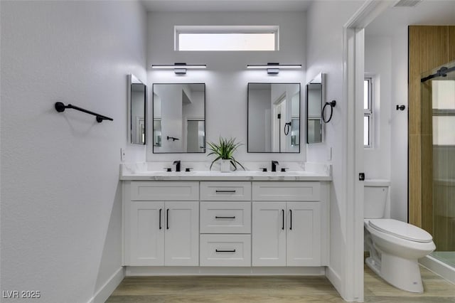 bathroom featuring toilet, a shower with shower door, hardwood / wood-style floors, and vanity