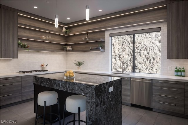 kitchen with a kitchen bar, stainless steel appliances, decorative backsplash, sink, and a center island