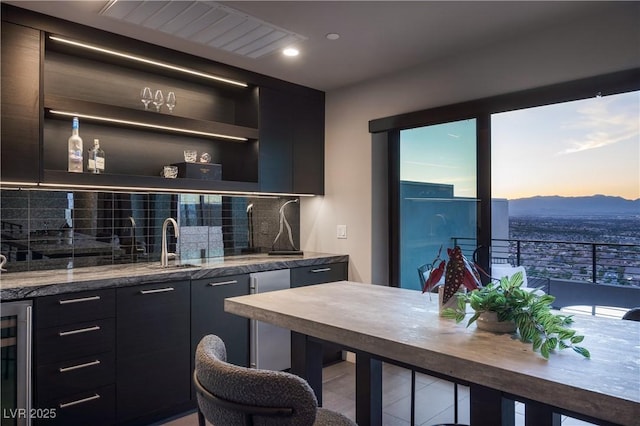 bar featuring wine cooler, sink, backsplash, a mountain view, and light stone counters