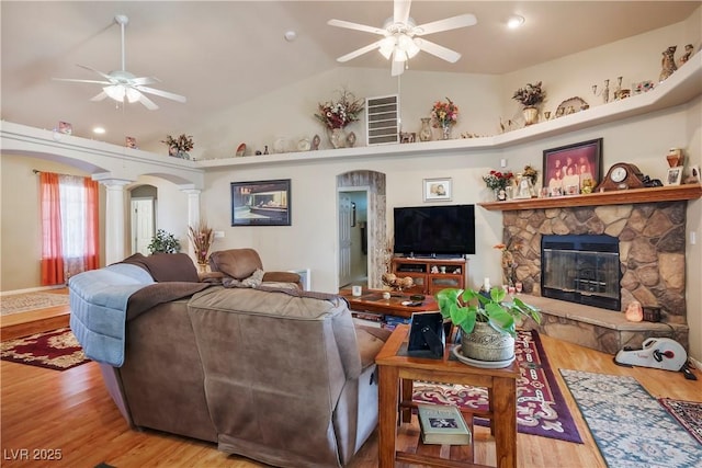 living room featuring ceiling fan, a fireplace, hardwood / wood-style flooring, and decorative columns