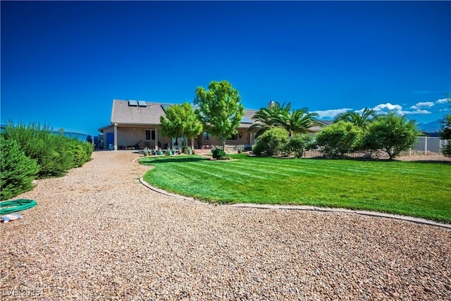 rear view of house with solar panels and a yard