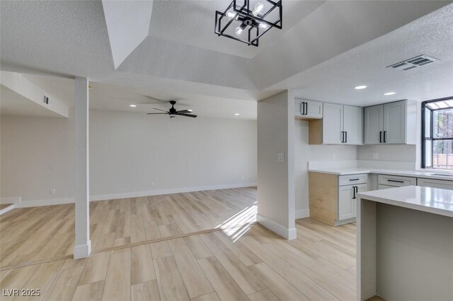 kitchen with a textured ceiling, ceiling fan, light hardwood / wood-style floors, and gray cabinets