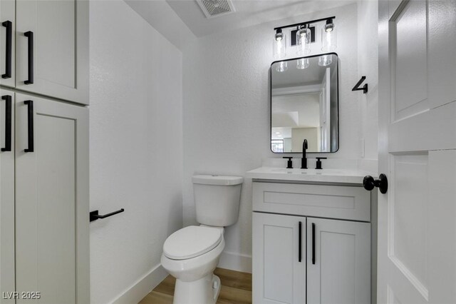 bathroom with toilet, vanity, and hardwood / wood-style flooring