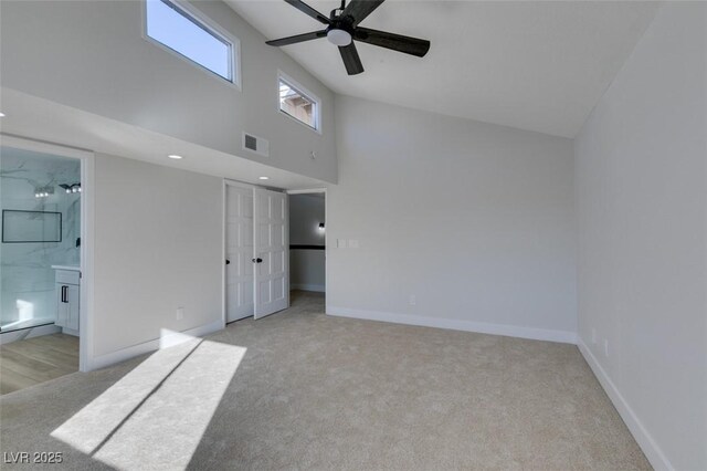 carpeted spare room with ceiling fan and a towering ceiling