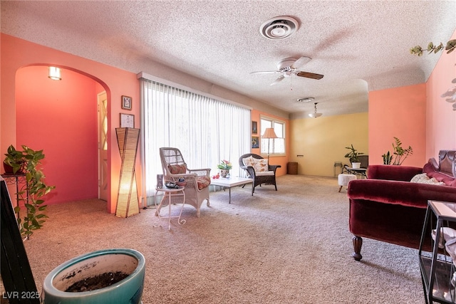 carpeted living room with ceiling fan and a textured ceiling