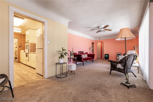 sitting room featuring light carpet, ceiling fan, and a textured ceiling