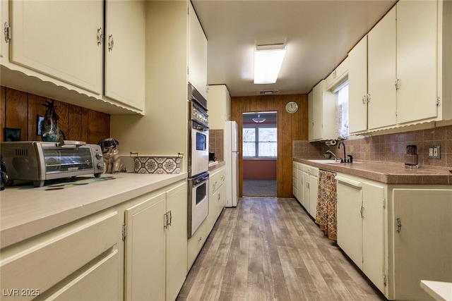 kitchen featuring sink, white appliances, white cabinets, and light wood-type flooring