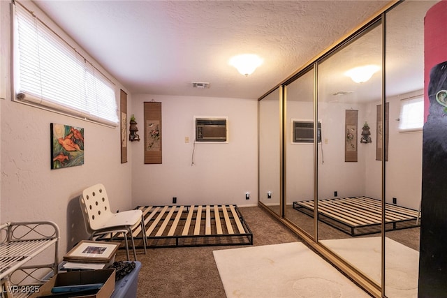 interior space featuring an AC wall unit, a textured ceiling, and carpet flooring