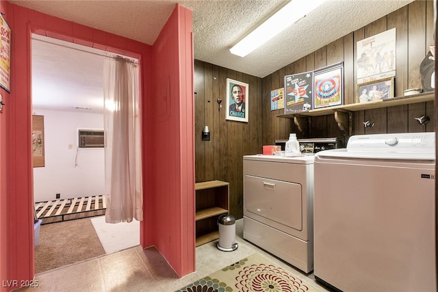 laundry room with a textured ceiling, separate washer and dryer, and wooden walls