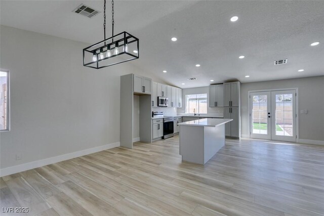 kitchen with light hardwood / wood-style floors, appliances with stainless steel finishes, gray cabinetry, and a kitchen island