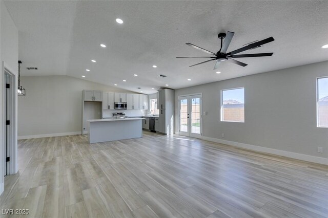 unfurnished living room with light wood-type flooring, ceiling fan, a textured ceiling, and french doors