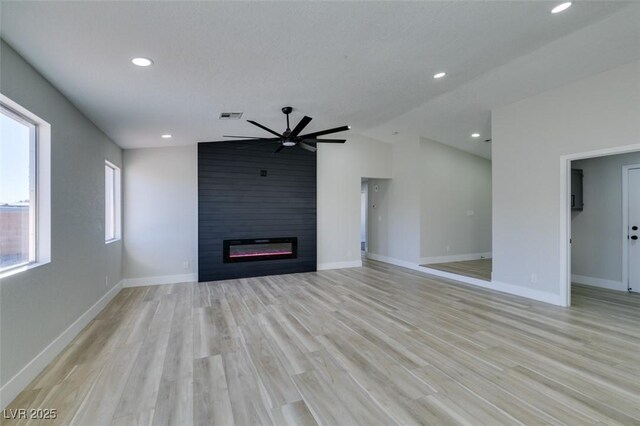 unfurnished living room with vaulted ceiling, ceiling fan, a fireplace, and light hardwood / wood-style flooring