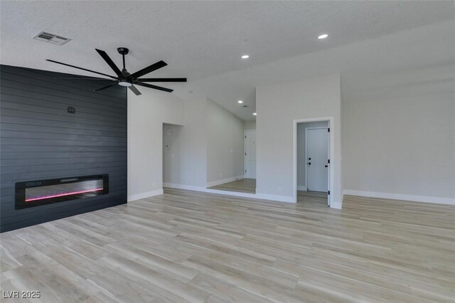 unfurnished living room featuring ceiling fan, a fireplace, light wood-type flooring, a textured ceiling, and high vaulted ceiling