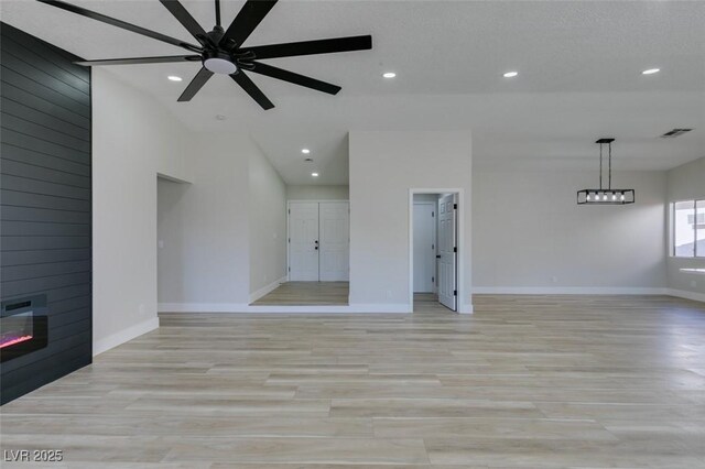 unfurnished living room with ceiling fan, a large fireplace, and light hardwood / wood-style floors