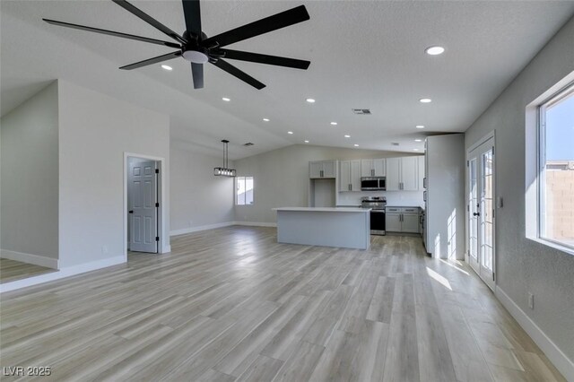 unfurnished living room with vaulted ceiling, ceiling fan, and light wood-type flooring