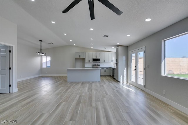 unfurnished living room with a textured ceiling, lofted ceiling, french doors, light hardwood / wood-style floors, and ceiling fan