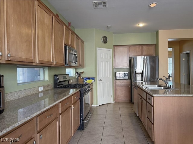 kitchen featuring light tile patterned floors, sink, light stone counters, and stainless steel appliances