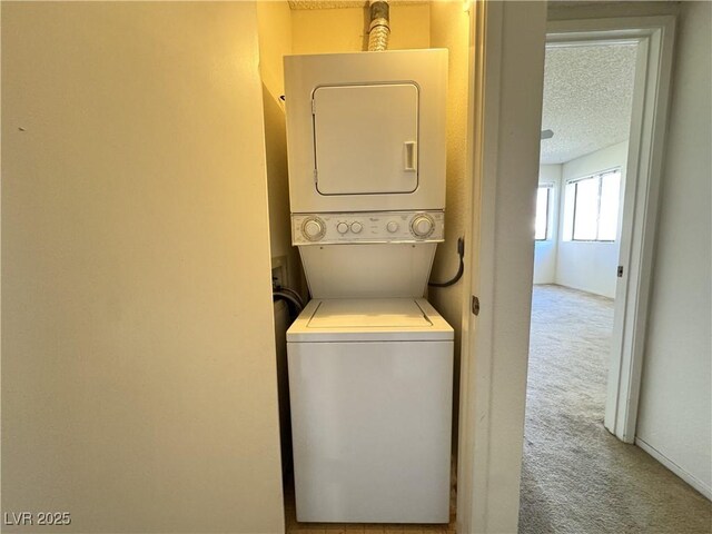 washroom with a textured ceiling, carpet flooring, and stacked washer / dryer