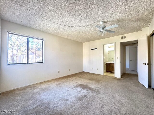 unfurnished bedroom with ceiling fan, connected bathroom, light carpet, and a textured ceiling