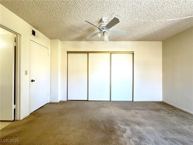 unfurnished bedroom featuring ceiling fan, a closet, carpet floors, and a textured ceiling