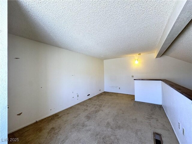 unfurnished room featuring light colored carpet, lofted ceiling with beams, and a textured ceiling