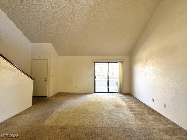 carpeted empty room featuring a textured ceiling and vaulted ceiling