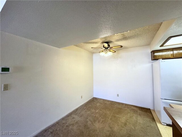 interior space with a textured ceiling, ceiling fan, and light colored carpet