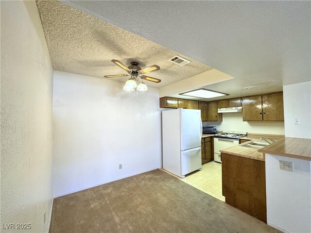 kitchen with kitchen peninsula, ceiling fan, white appliances, a textured ceiling, and sink