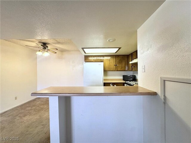 kitchen with ceiling fan, light colored carpet, kitchen peninsula, a textured ceiling, and white refrigerator