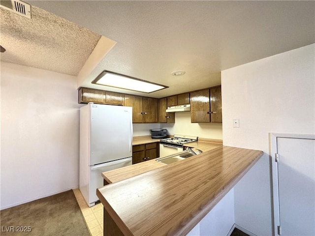 kitchen with a textured ceiling, sink, kitchen peninsula, and white appliances