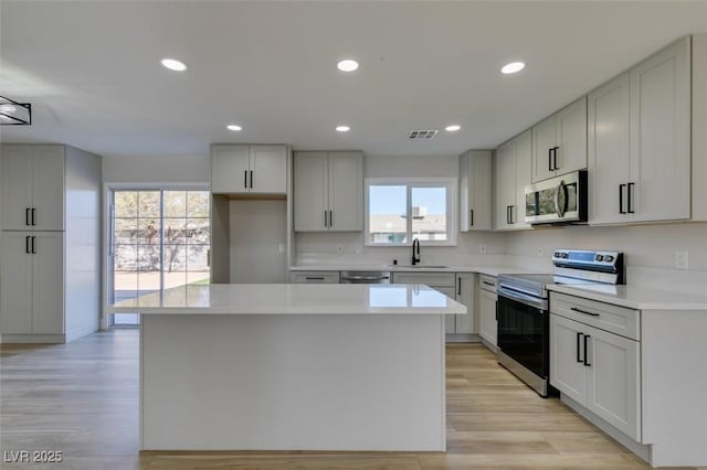 kitchen with appliances with stainless steel finishes, sink, plenty of natural light, and a center island