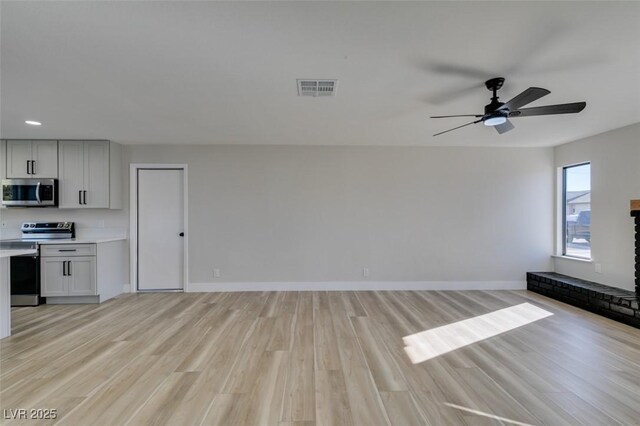 unfurnished living room featuring a fireplace, ceiling fan, and light hardwood / wood-style floors