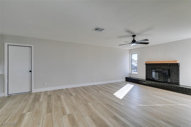 unfurnished living room featuring ceiling fan, a brick fireplace, and light hardwood / wood-style flooring