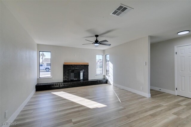 unfurnished living room featuring light wood-type flooring, ceiling fan, and a fireplace