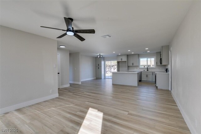 unfurnished living room with ceiling fan, sink, and light hardwood / wood-style floors