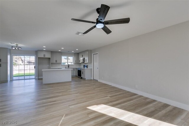 unfurnished living room with ceiling fan, sink, and light hardwood / wood-style floors