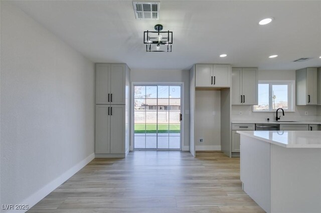 kitchen featuring a wealth of natural light, dishwasher, sink, and light hardwood / wood-style flooring