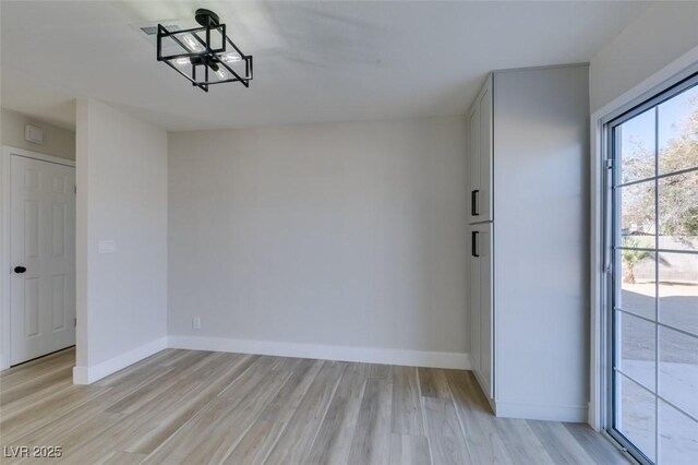 empty room featuring an inviting chandelier and light hardwood / wood-style flooring