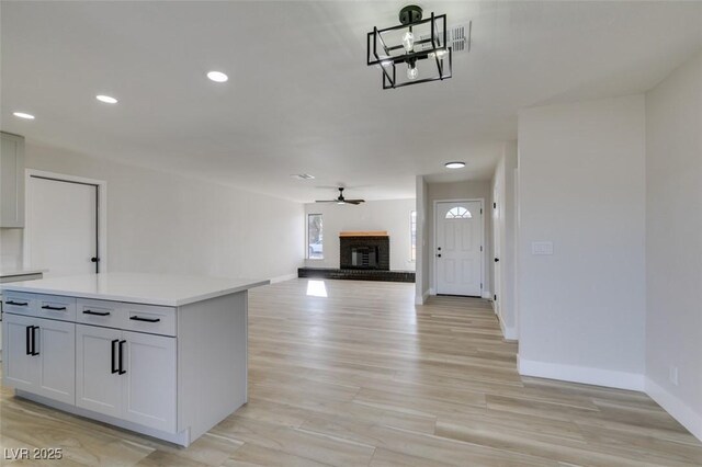 interior space with ceiling fan, a fireplace, and light hardwood / wood-style flooring