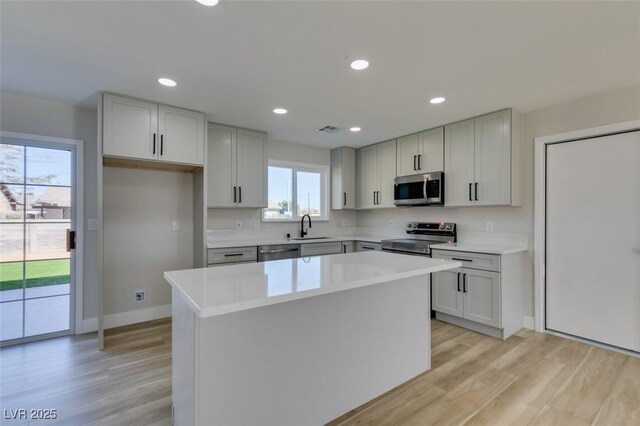 kitchen featuring light hardwood / wood-style floors, sink, appliances with stainless steel finishes, and a center island